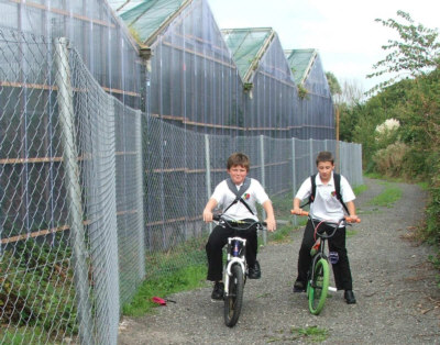 Students Cycling by Greenhouses